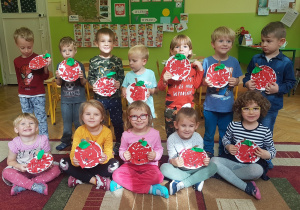 Zdjęcie grupowe – dzieci prezentują prace plastyczne: jabłka wykonane z papierowych talerzyków i kolorowego papieru.